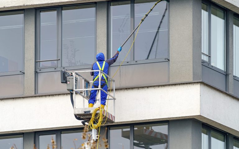 A worker washes windows in a multi-story building.